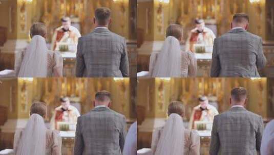 新娘和新郎在婚礼上背靠背站在天主教堂里高清在线视频素材下载