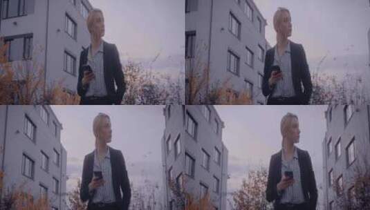 女人拿着手机站在城市建筑里高清在线视频素材下载