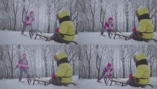 母亲向坐在雪橇上的小孩扔雪高清在线视频素材下载
