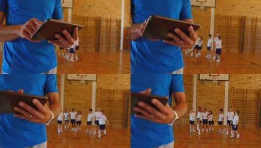 篮球教练在学校篮球场使用数字平板电脑4k高清在线视频素材下载