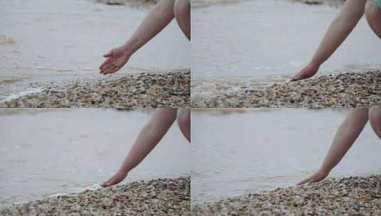 女人用手穿过肮脏的海水和岸上的鹅卵石特写高清在线视频素材下载