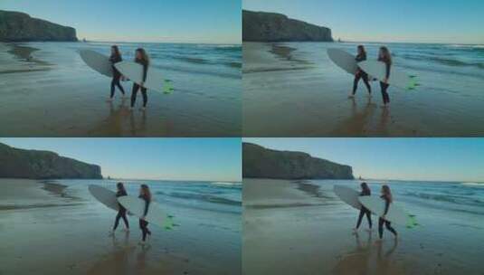 女孩们拿着冲浪板行走在沙滩上高清在线视频素材下载