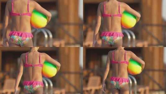 一个穿着泳衣拿着充气球的女孩在游泳池附近散步高清在线视频素材下载