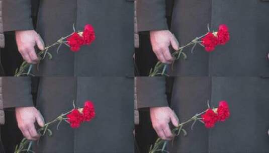 一个男人手里拿着两朵红色康乃馨高清在线视频素材下载
