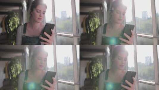 女人在窗户边玩手机高清在线视频素材下载