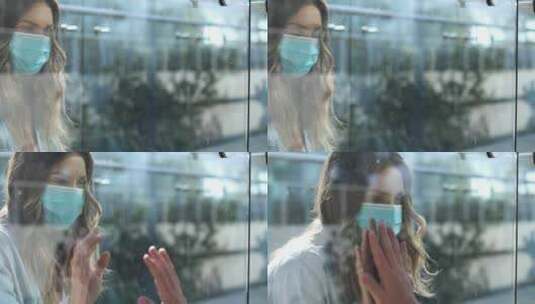戴口罩的女人趴在玻璃窗前高清在线视频素材下载