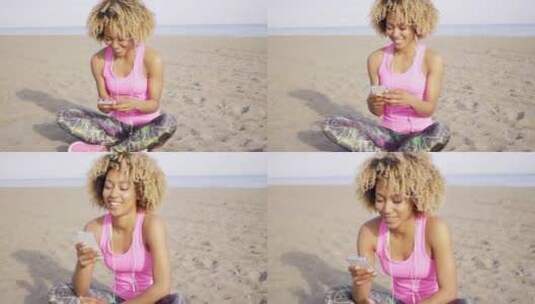 咧嘴笑的女人坐在海滩上听音乐高清在线视频素材下载