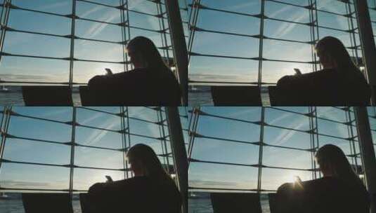 女人在机场航站楼窗户前使用手机的剪影高清在线视频素材下载