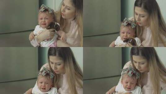 接种疫苗后，年轻美丽的母亲让女儿平静下来。女儿拿着一个毛绒玩具哭了。慢动作。高清在线视频素材下载