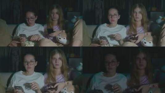 两个女孩坐在家里舒适的沙发上看电视高清在线视频素材下载