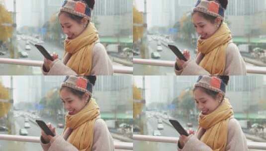 都市女青年秋天城市街头玩手机戴着围巾高清在线视频素材下载