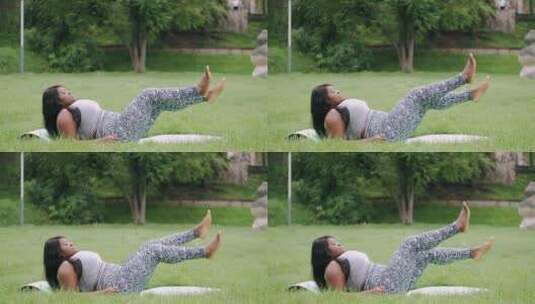 草地上做抬腿运动的女人高清在线视频素材下载