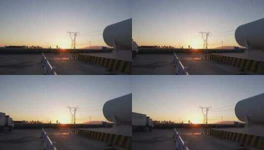 夕阳下高压电线塔附近巨大的储气罐航拍高清在线视频素材下载
