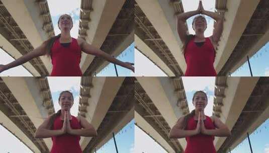一名穿着红色训练服的成年女子站在桥下双手合十高清在线视频素材下载