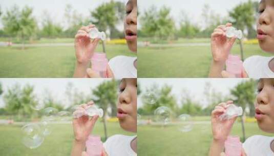 在公园草坪上玩吹泡泡游戏的中国女孩高清在线视频素材下载
