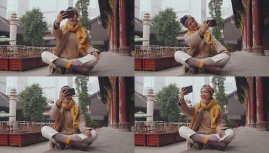 女孩坐在寺庙地上用手机视频电话分享高清在线视频素材下载