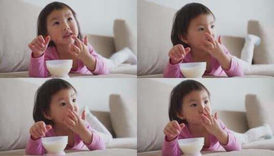 可爱小朋友趴在沙发上用手沾酸奶吃高清在线视频素材下载