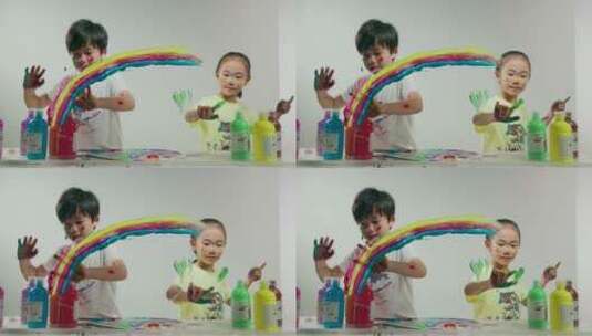 小男孩和小女孩用涂满颜料的手画画高清在线视频素材下载