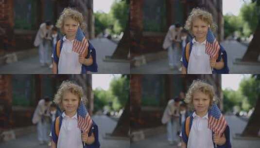 小男孩拿着美国国旗站在学校附近高清在线视频素材下载
