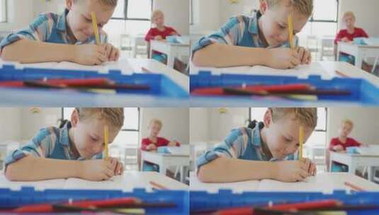 快乐的高加索男孩坐在学校桌子前写作的视频高清在线视频素材下载
