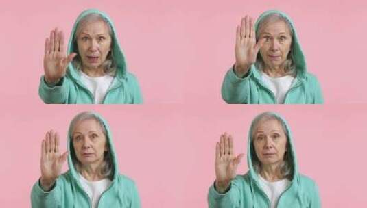谨慎的老年妇女举着停止手掌标志绿色连帽衫高清在线视频素材下载