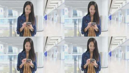 女人在机场低头微笑使用手机高清在线视频素材下载