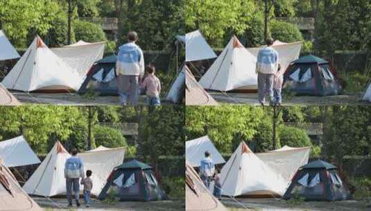男子牵着小孩经过露营帐篷高清在线视频素材下载