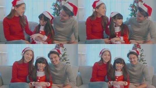 亚洲幸福家庭的肖像戴着圣诞老人帽，坐在客厅里。高清在线视频素材下载
