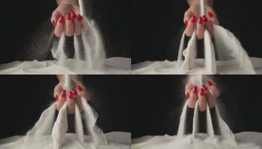 手里拿着一把白色干沙子的女人在黑色工作室里用手指洒沙子高清在线视频素材下载