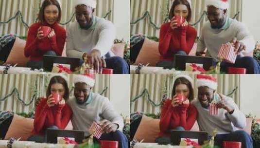 戴着圣诞帽的快乐多样化夫妇在家打圣诞笔记本电脑视频电话的视频高清在线视频素材下载