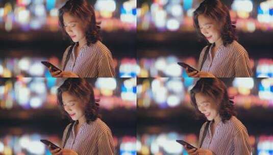 快乐中国女青年夜晚玩手机霓虹灯光背景高清在线视频素材下载