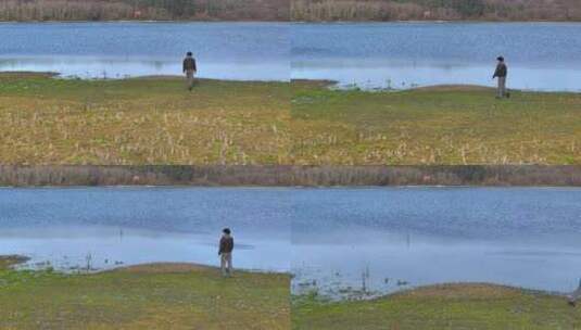 白天，一名男子独自走向平静的湖边。无人机高清在线视频素材下载