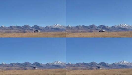 雪山下枯黄草原行驶的白色车辆高清在线视频素材下载