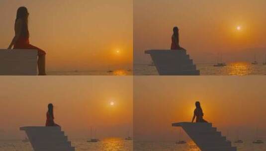 高台上夕阳下海边海风中看日落的女孩高清在线视频素材下载