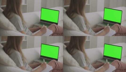 女人看着绿幕笔记本电脑记笔记高清在线视频素材下载
