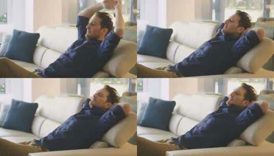 一个男人在家里的沙发上放松，抱着枕头，在高清在线视频素材下载