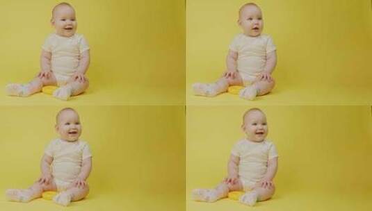 黄色背景下快乐的女婴漂亮的婴儿微笑着望着高清在线视频素材下载