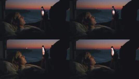 女人在海边露营时玩手机高清在线视频素材下载