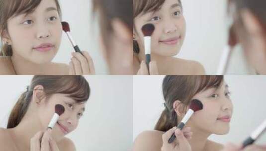 美丽年轻的亚洲女人微笑着用脸颊刷化妆。高清在线视频素材下载