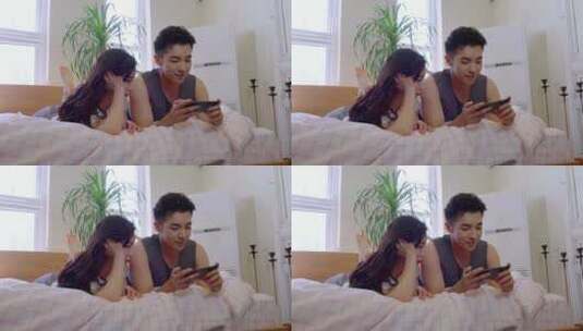 青年情侣趴在床上玩手机高清在线视频素材下载