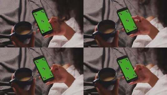 女人在早上端着咖啡看绿屏智能手机高清在线视频素材下载