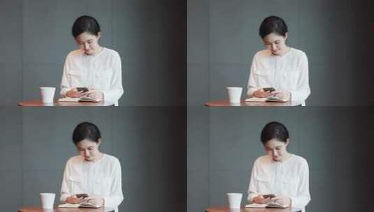 一个女性坐在咖啡馆看手机展示手机高清在线视频素材下载