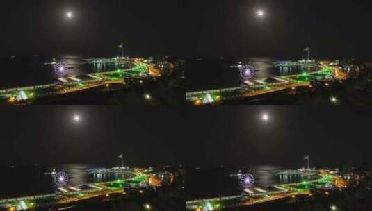 海洋和月球路径交通背景下的夜间摩天轮大城高清在线视频素材下载