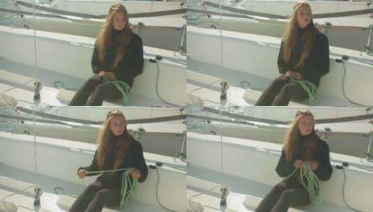 一个长发女孩坐在白色运动游艇的甲板上，解开绳子准备船高清在线视频素材下载