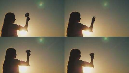 无忧无虑的小女孩在日落时分玩纸飞机高清在线视频素材下载