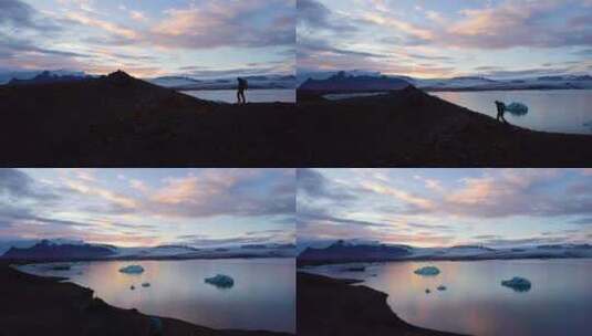 日落时分，徒步旅行者在冰冷的海洋旁的岩石高清在线视频素材下载