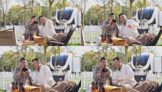 两个老年男人坐在房车露营院子里看数码相机高清在线视频素材下载