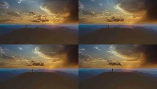 无人机拍摄黄昏时男人站在山顶上高清在线视频素材下载