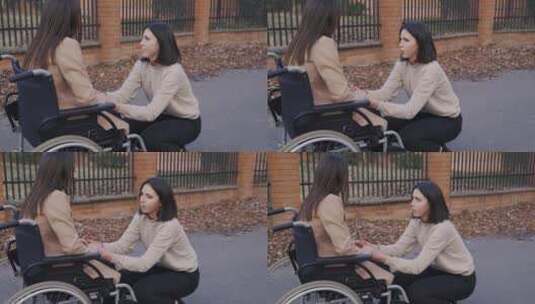 女人蹲着和坐在轮椅上的朋友聊天高清在线视频素材下载