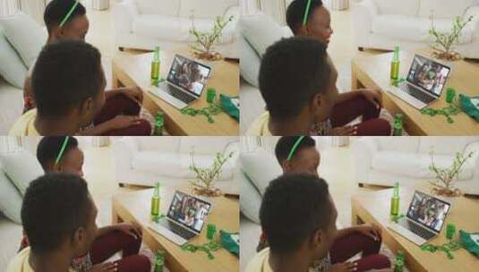 非裔美国夫妇在笔记本电脑视频通话中与朋友庆祝圣帕特里克节高清在线视频素材下载